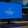 A computer monitor on an office desk displaying a blue Windows screen with a progress bar and the text "Automatic Repair in progress."